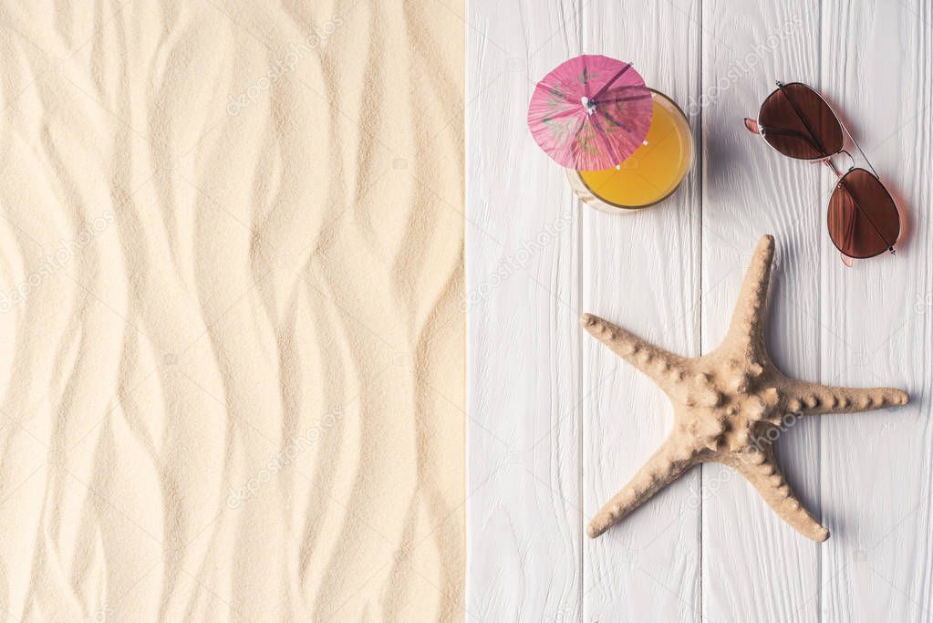 Cocktail with starfish and sunglasses on sandy beach