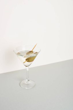 Beyaz arka planda izole edilmiş gri yüzeyde zeytinli vermut.