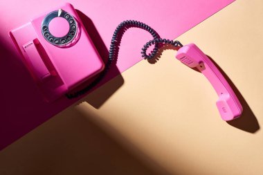 Renkli yüzeyinde gölgesi olan pembe telefonun üst görünümü