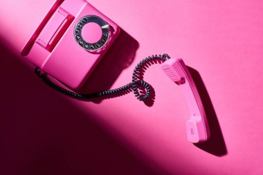 Parlak yüzeyinde gölgesi olan klasik pembe telefonun üst görüntüsü
