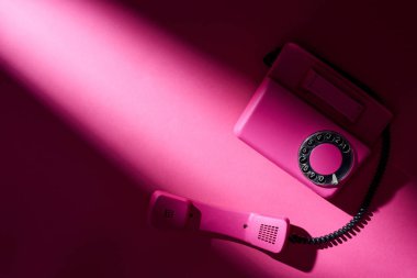 Parlak yüzeyinde gölgesi olan klasik pembe telefonun üst görüntüsü