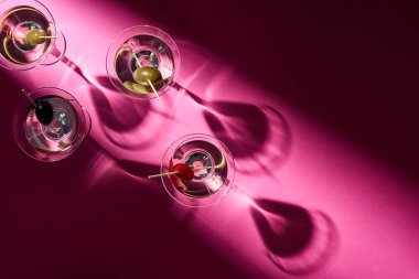 Pembe arka planda zeytinli martini kokteylleri.
