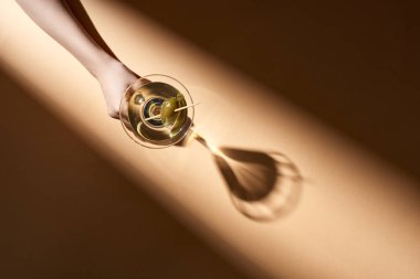 Bej arka planda bir kadeh martini tutan bir kadın görüntüsü.