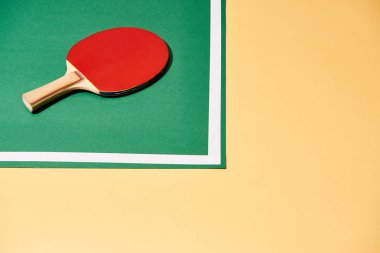 Sarı yüzeydeki masada yüksek açılı tenis raketi manzarası