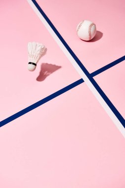 Pembe yüzeyde mavi çizgileri olan beysbol ve badminton topları.