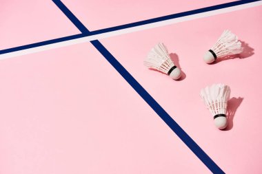 Badminton mekikleri pembe yüzeyde gölgeli mavi ve beyaz çizgilerle