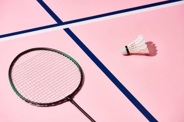 Badminton raketi ve mavi çizgileri olan pembe arka planda bir mekik.