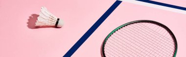 Badminton raketi ve mavi çizgili, panoramik çekimli, pembe arka planda mekik siki.