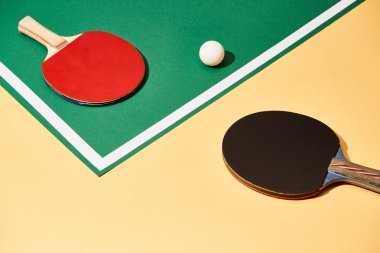 Two table tennis rackets and ball on green and yellow surface with white line clipart