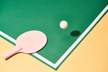 Table tennis racket and ball on green and yellow surface  clipart