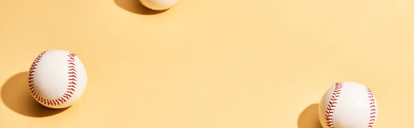 Белые бейсбольные мячи на желтой поверхности, панорамный снимок

