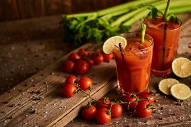 bloody mary cocktail in glasses on wooden background with salt, pepper, lime, tomatoes and celery clipart