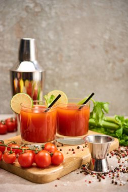 bloody mary cocktail in glasses with straws and lime on wooden board near salt, pepper, tomatoes and celery clipart