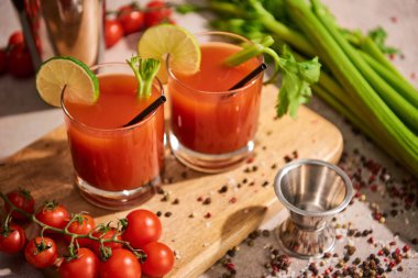 bloody mary cocktail in glasses on wooden board near salt, pepper, lime slices, tomatoes and celery clipart