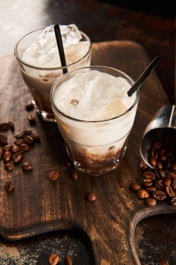 white russian cocktail in glasses with straws on wooden board with coffee grains clipart