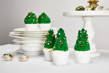 Lezzetli Noel ağacı çörekleri tabakları ve parlak mücevherleri gri yüzeyde izole edilmiş.