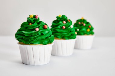 Gri yüzeyde sıralanmış lezzetli Noel ağacı keklerinin seçici odağı