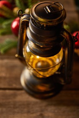 Süslü, antika bir gaz lambasını ladin dalları ve ahşap masada noel toplarıyla kapatın.