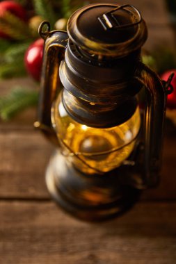 close up of decorative vintage oil lamp with spruce branches and christmas balls on wooden table clipart