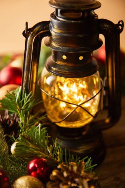 close up of decorative vintage oil lamp with blurred lights, spruce branches and christmas balls clipart