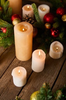 Ladin dallı mumlar yakmak ve ahşap masada noel topları.