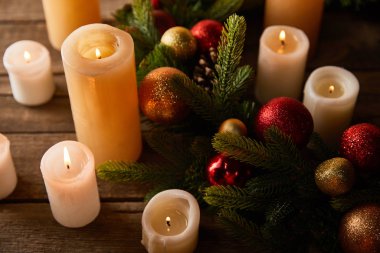 Çelenk ile mum yakmak, ahşap masada kırmızı ve altın noel topları