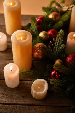 Ladin dallı mumlar yakmak ve ahşap masada noel topları.