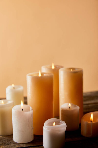 close up of burning candles on wooden table on beige