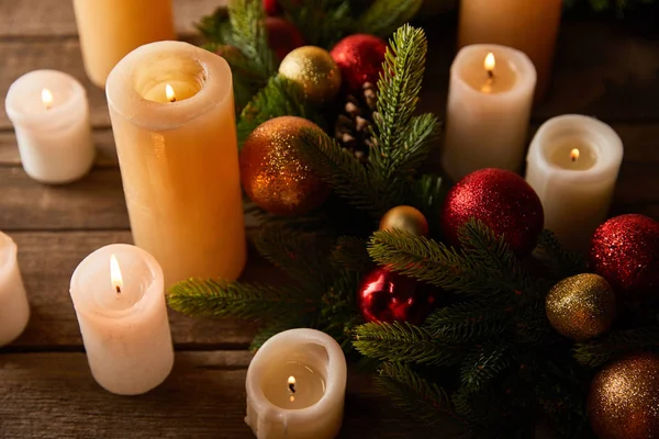 用云杉花环点着蜡烛 木桌上挂着金红二色的圣诞球 — 图库照片