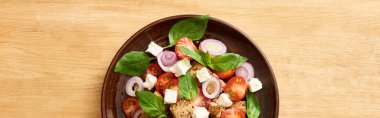 top view of fresh Italian vegetable salad panzanella served on plate on wooden table, panoramic shot clipart