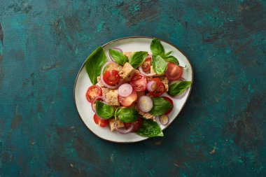 Lezzetli İtalyan sebze salatasının üst görüntüsü yeşil yüzeyde servis edilen tabakta.