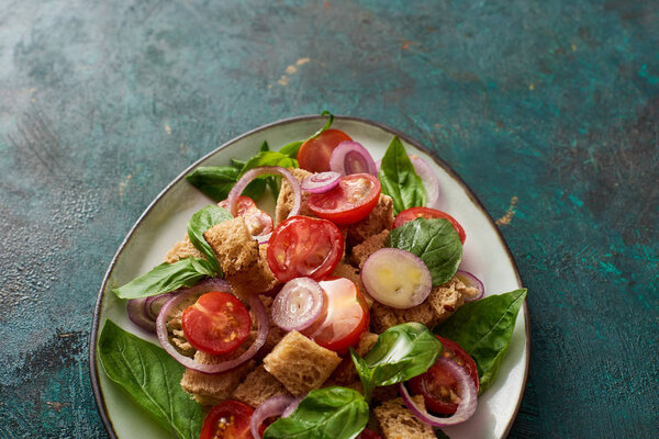 top view of fresh Italian vegetable salad panzanella served on plate on textured table