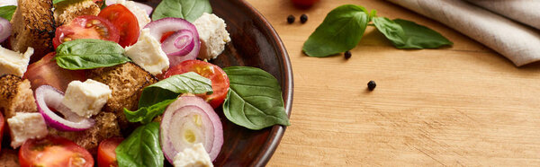 вкусный итальянский овощной салат panzanella подается на тарелке на деревянном столе, панорамный снимок
