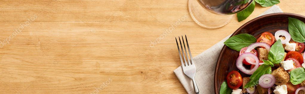Top view of delicious Italian vegetable salad panzanella served on plate on wooden table near fork on napkin and red wine, panoramic shot — Stock Image Top View Delicious Italian Vegetable Salad Panzanella Served Plate Wooden Stock Photo