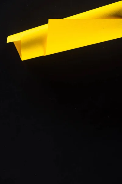 Yellow rolled paper isolated on black — Stock Photo