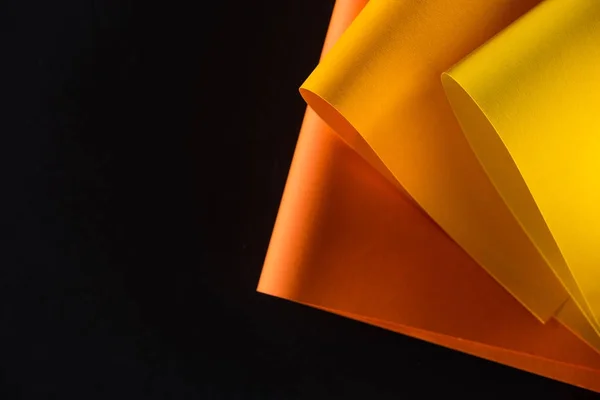 Papeles de color naranja y amarillo aislados en negro - foto de stock
