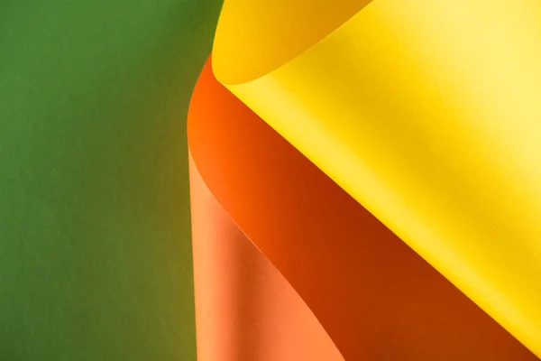 Papeles amarillos y anaranjados sobre fondo verde - foto de stock