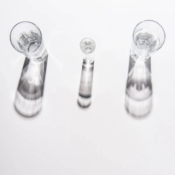 High angle view of different sized glasses with water on white table — Stock Photo