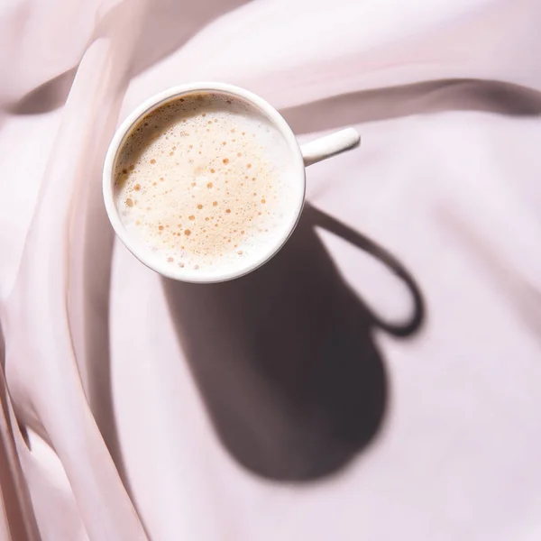 Vista superior da xícara de café na toalha de mesa rosa com sombra — Fotografia de Stock
