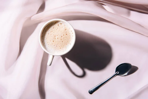 Vista superior da xícara de café e colher na toalha de mesa rosa — Fotografia de Stock