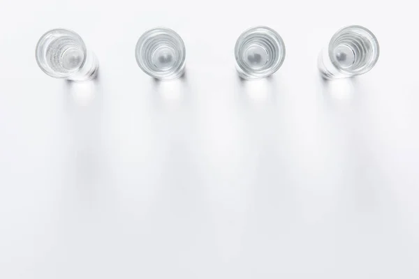 Draufsicht auf eine Reihe kleiner Gläser mit Wasser auf weißem Tisch — Stockfoto