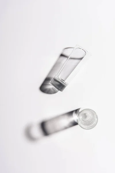 Top view of one glass with water and one empty glass on white surface — Stock Photo