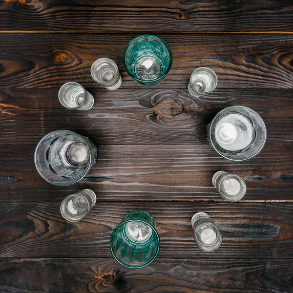 Vista superior do círculo com óculos de diferentes tamanhos com água na mesa de madeira — Fotografia de Stock