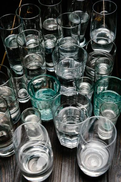 Vista ad angolo alto di bicchieri di diverse dimensioni con acqua sul tavolo di legno — Foto stock