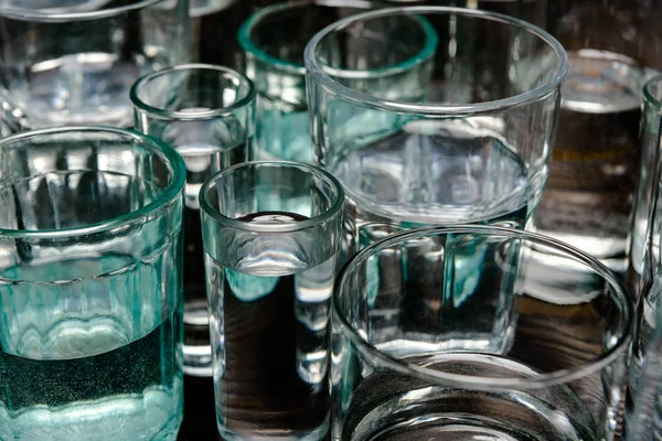 Close up view of different sized glasses with water on wooden table — Stock Photo