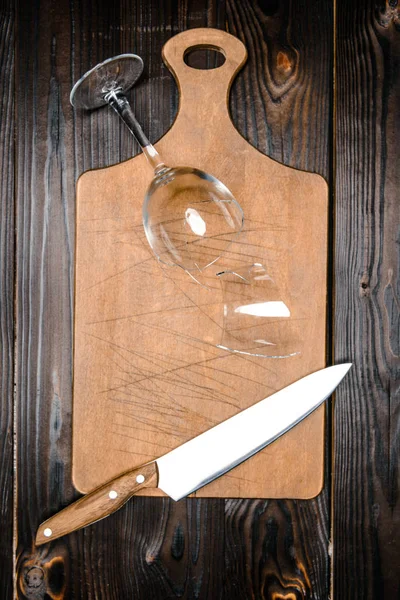 Top view of broken wineglass and knife with wooden board on table — Stock Photo
