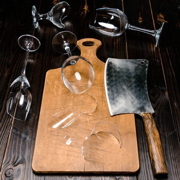 High angle view of broken wineglasses and axe with wooden board on table — Stock Photo