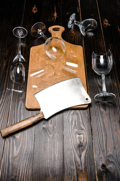 High angle view of broken wineglasses and axe with wooden board on table — Stock Photo