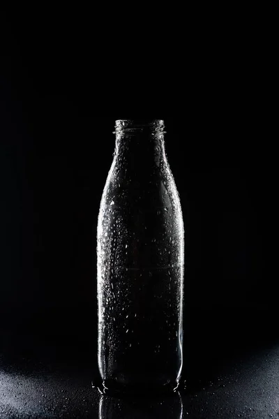 One transparent empty glass bottle with condensate on black — Stock Photo