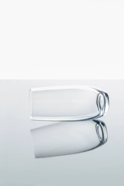Un vaso sobre superficie reflectante blanca - foto de stock